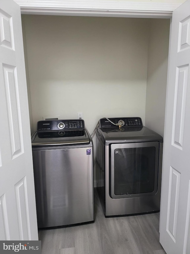 laundry room featuring laundry area, washing machine and clothes dryer, and wood finished floors