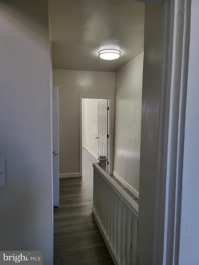 corridor with baseboards and dark wood finished floors