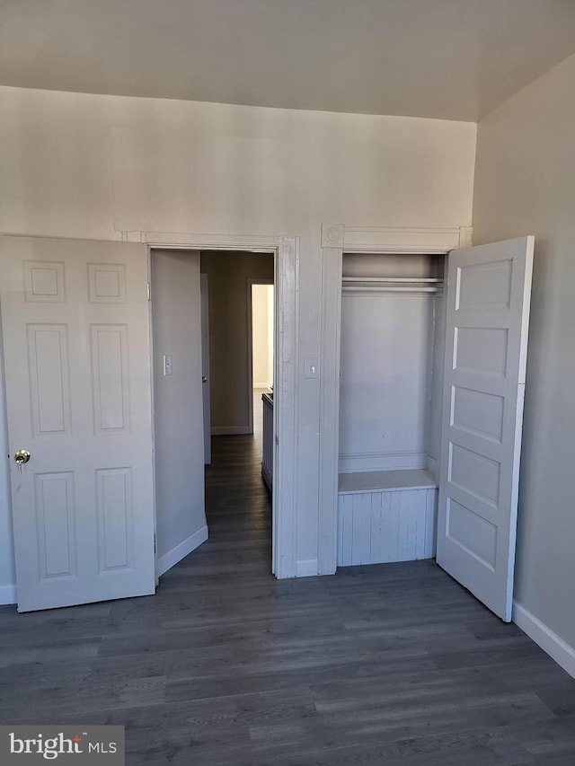 unfurnished bedroom featuring a closet, baseboards, and dark wood finished floors