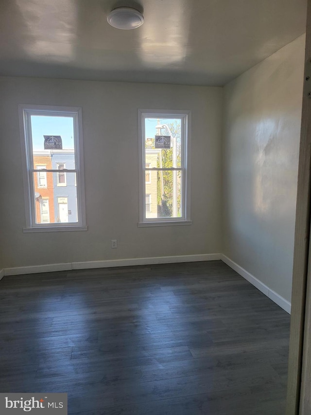 empty room with dark wood-style floors and baseboards