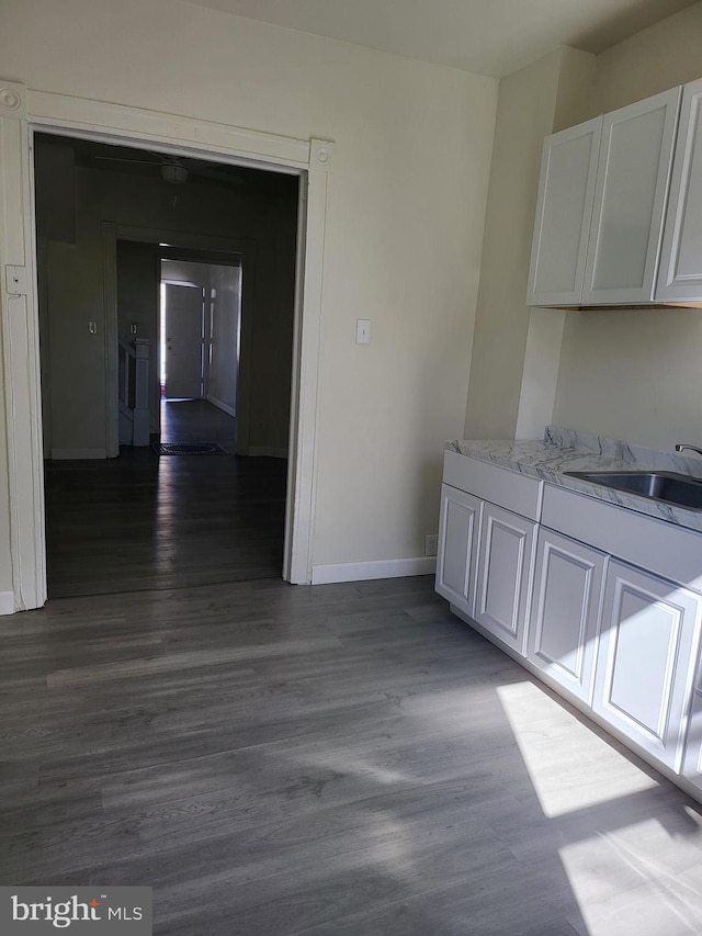 interior space featuring a sink, baseboards, and dark wood-style floors