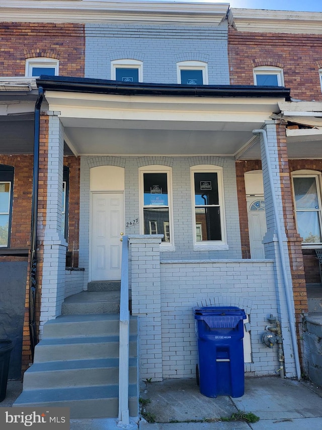 entrance to property featuring covered porch and brick siding