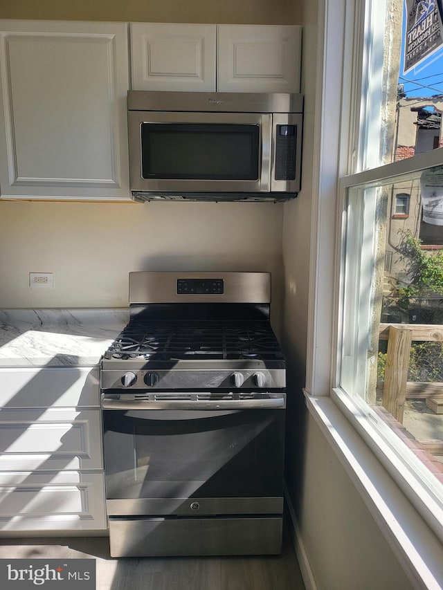kitchen with white cabinetry, light countertops, a wealth of natural light, and appliances with stainless steel finishes