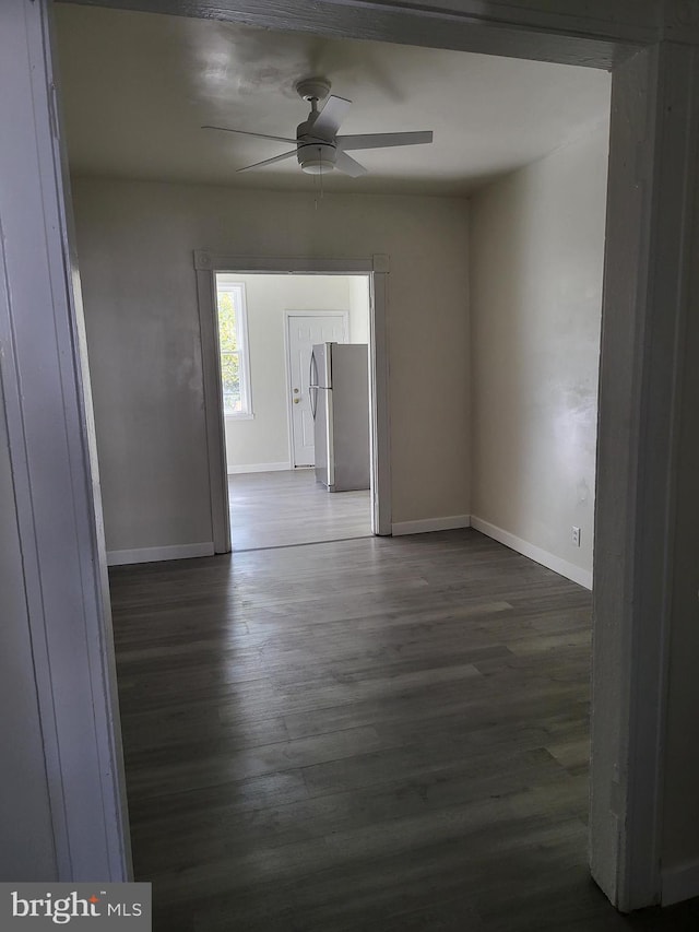 empty room with dark wood-style floors, baseboards, and a ceiling fan