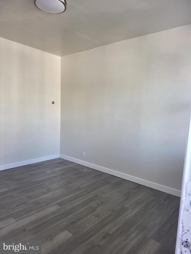 empty room featuring baseboards and dark wood finished floors