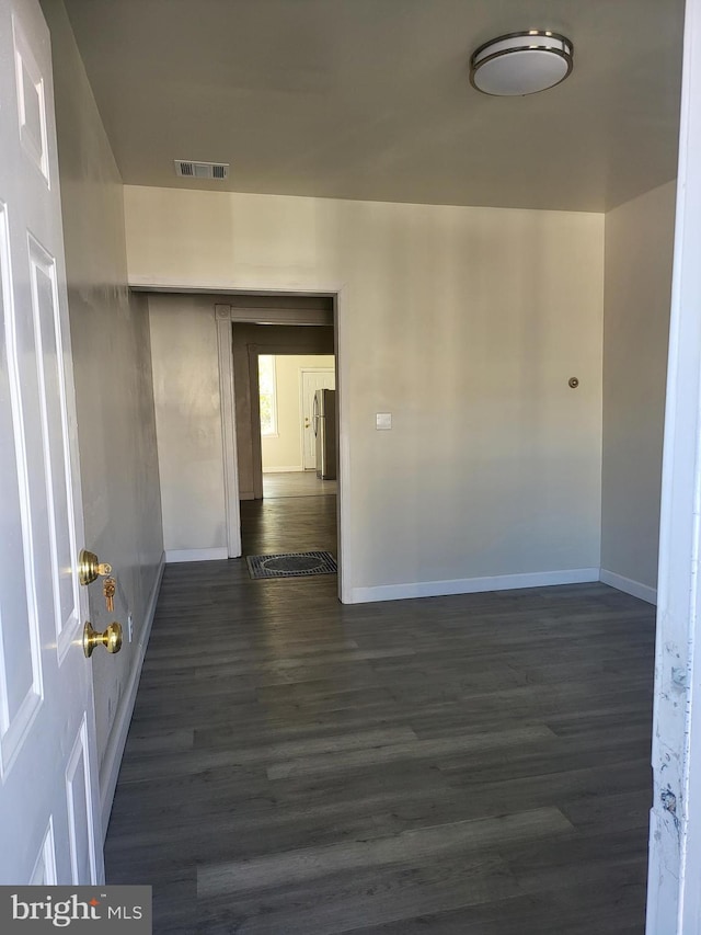 interior space with baseboards, dark wood finished floors, and visible vents