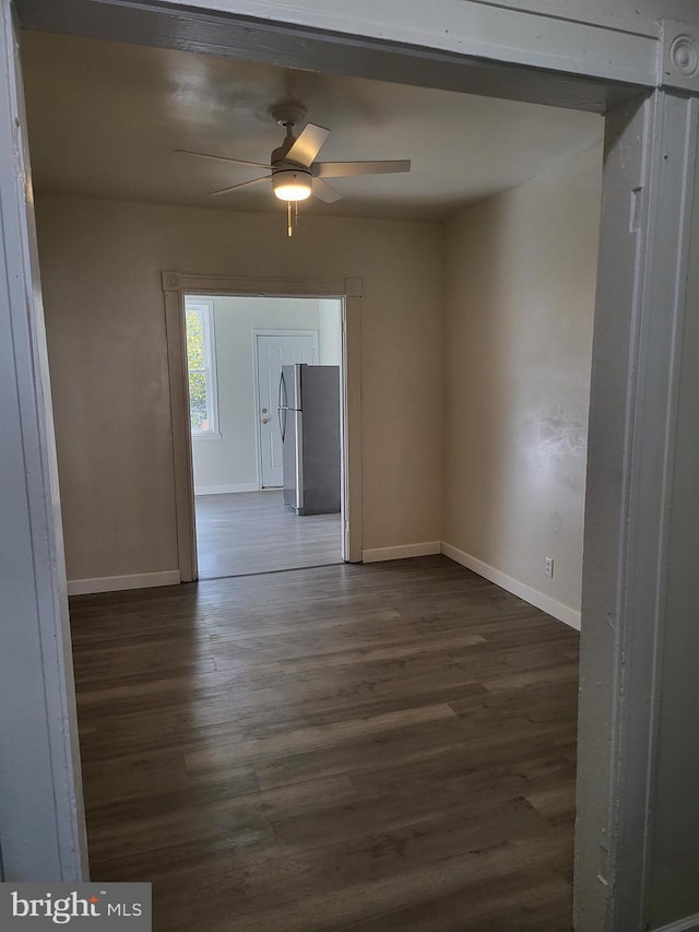 unfurnished room featuring ceiling fan, baseboards, and dark wood-style floors