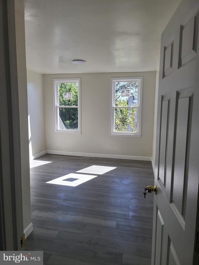 unfurnished room featuring baseboards and dark wood finished floors