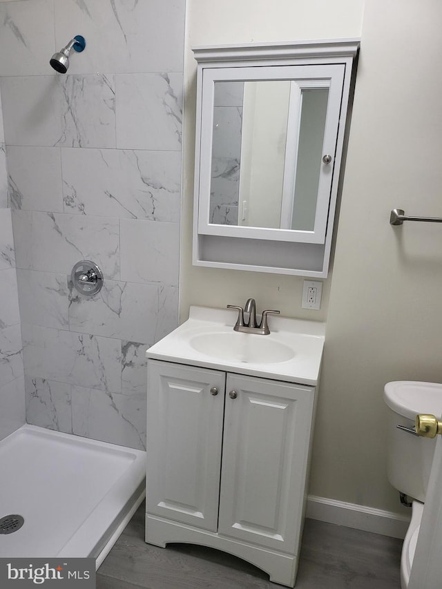full bath with toilet, vanity, baseboards, and a stall shower