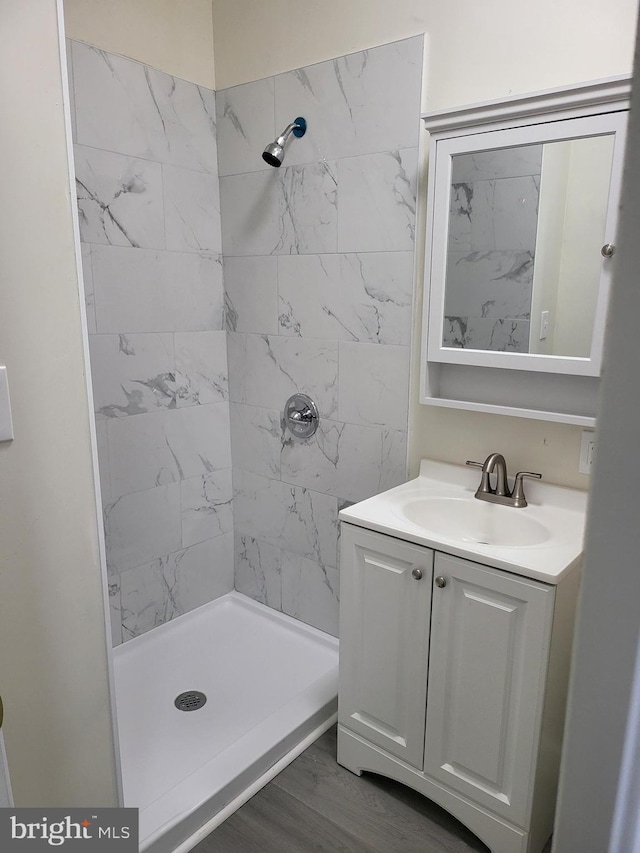 bathroom with a tile shower, hardwood / wood-style floors, and vanity