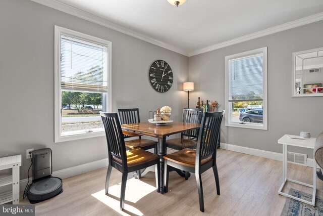 dining space with ornamental molding and light wood-type flooring