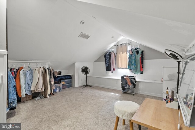 walk in closet with light carpet and vaulted ceiling