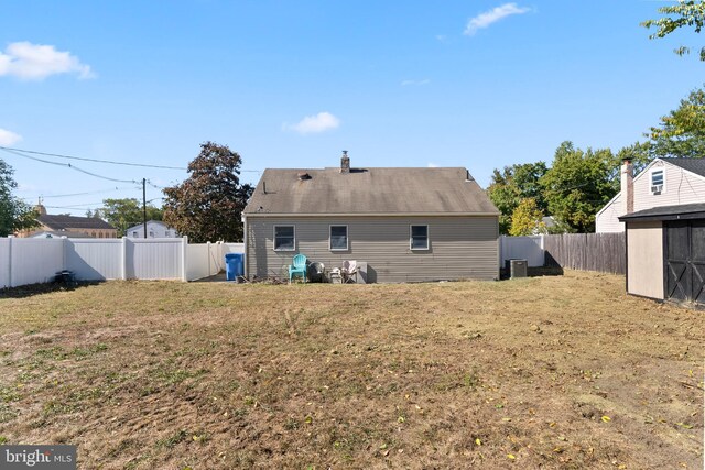 back of house featuring a shed and a lawn