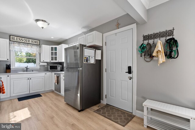 kitchen with light hardwood / wood-style floors, stainless steel fridge, sink, and white cabinetry