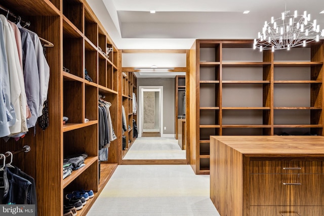 spacious closet with a notable chandelier and light carpet