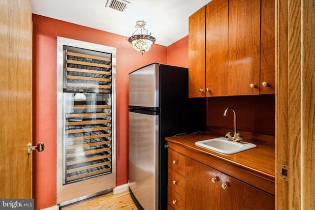 kitchen featuring light hardwood / wood-style flooring, beverage cooler, stainless steel fridge, and sink