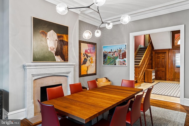 dining space featuring crown molding, a fireplace, and hardwood / wood-style flooring