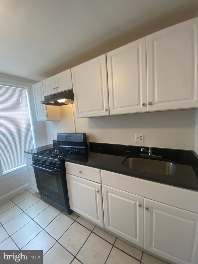 kitchen with black gas stove, white cabinets, light tile patterned floors, and sink