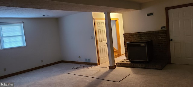 unfurnished living room featuring carpet floors, a brick fireplace, and a textured ceiling