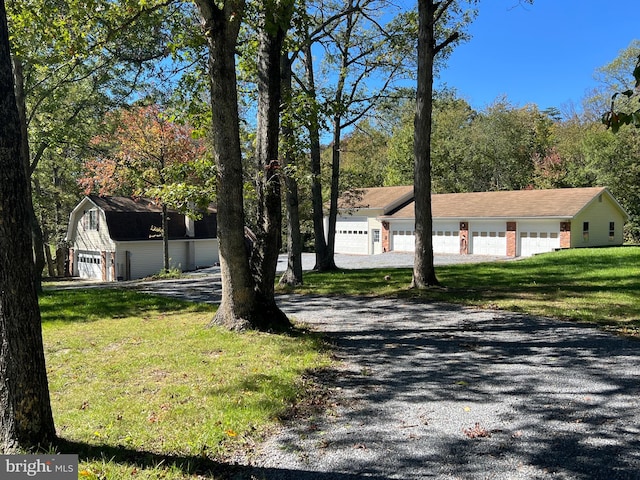 exterior space with a front yard, a garage, and an outbuilding