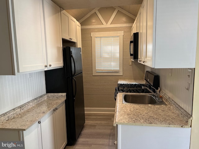 kitchen with lofted ceiling, sink, hardwood / wood-style floors, and white cabinets