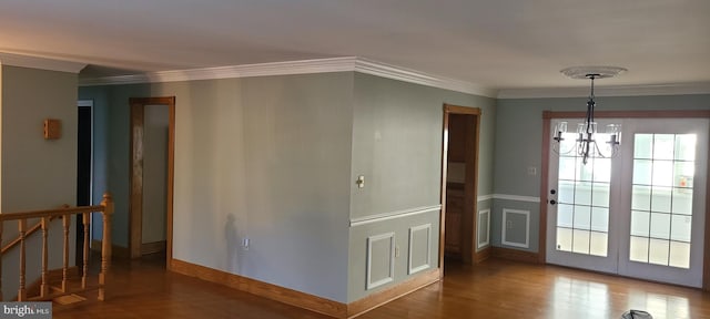 interior space with wood-type flooring, a notable chandelier, and ornamental molding