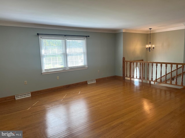 unfurnished room with crown molding, hardwood / wood-style floors, and an inviting chandelier