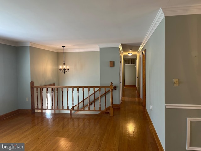 hallway with crown molding, a chandelier, and hardwood / wood-style flooring