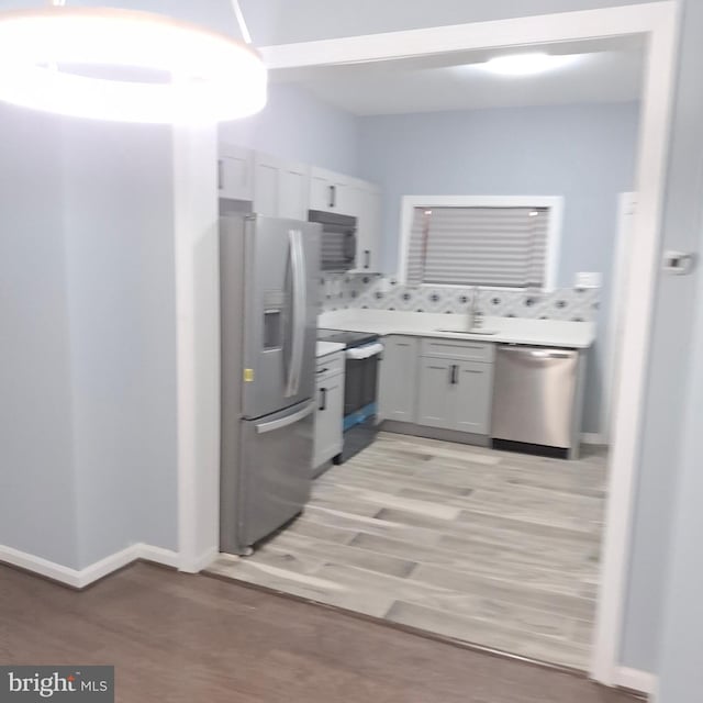 kitchen featuring white cabinets, stainless steel appliances, and light wood-type flooring