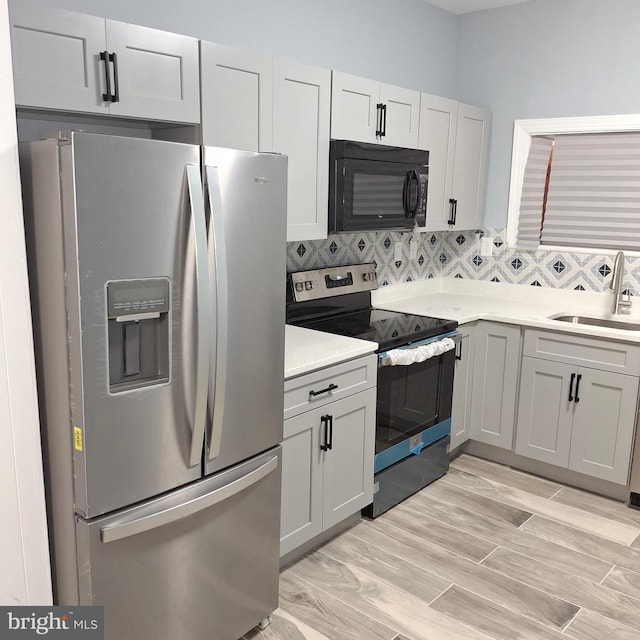 kitchen featuring decorative backsplash, sink, stainless steel appliances, and light hardwood / wood-style flooring