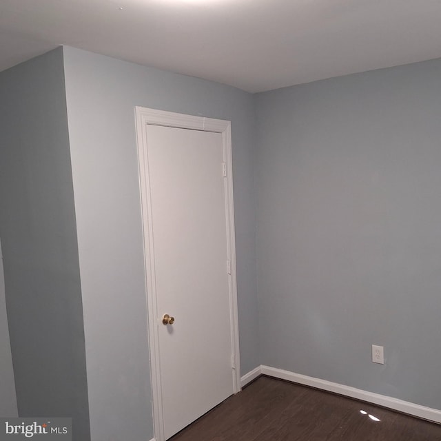 unfurnished room with dark wood-type flooring