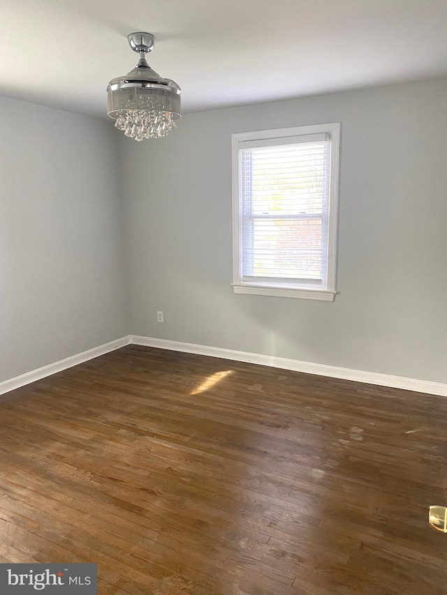 spare room with dark hardwood / wood-style flooring and a chandelier