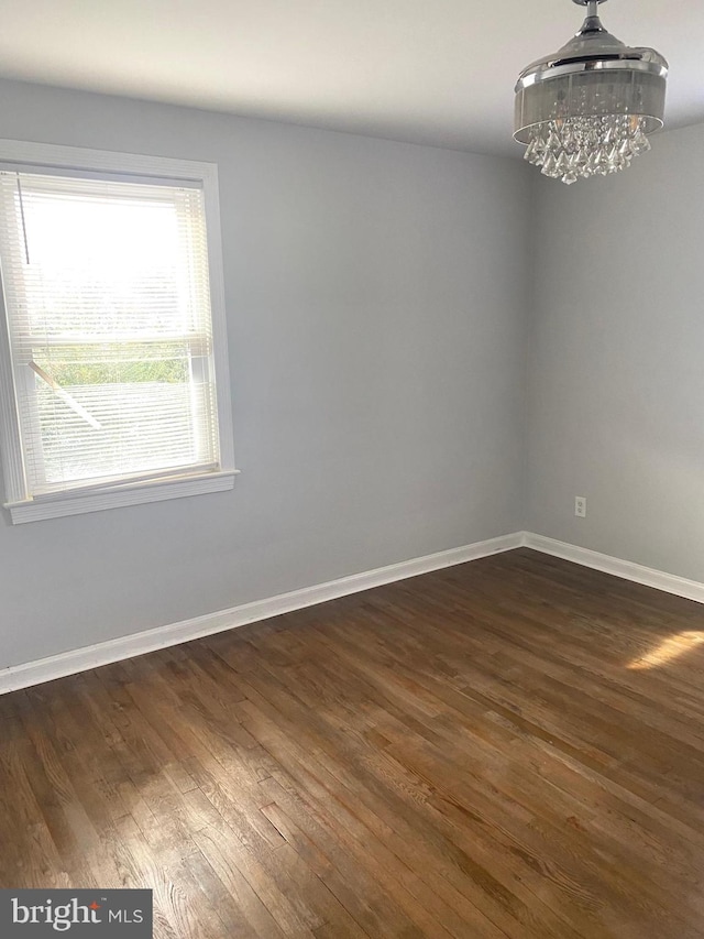 empty room featuring dark hardwood / wood-style flooring and a chandelier