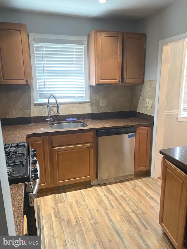 kitchen featuring sink, tasteful backsplash, light wood-type flooring, stainless steel dishwasher, and black range with gas stovetop