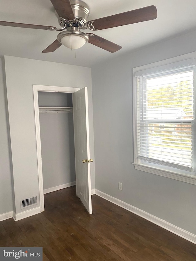 unfurnished bedroom featuring ceiling fan, dark hardwood / wood-style floors, and a closet