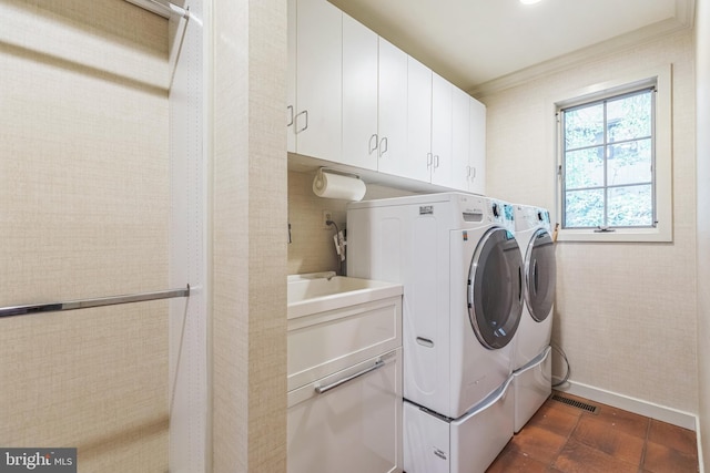 clothes washing area with washer and clothes dryer and cabinets