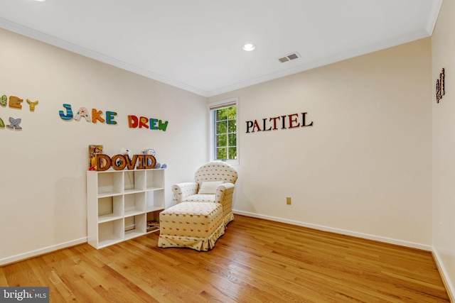 living area with ornamental molding and hardwood / wood-style floors