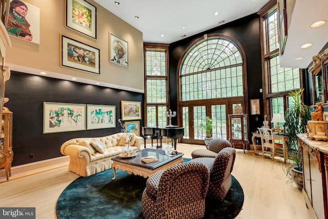 living room with light hardwood / wood-style floors and a towering ceiling