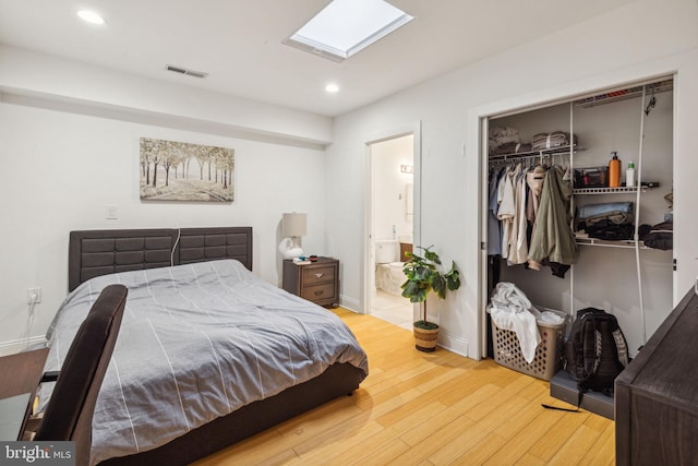 bedroom featuring connected bathroom, wood-type flooring, a closet, and a skylight