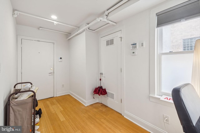 interior space with a wealth of natural light, baseboards, light wood-type flooring, and visible vents