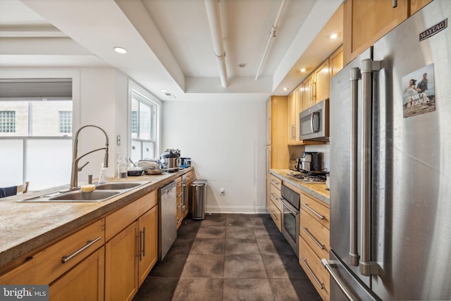 kitchen with recessed lighting, baseboards, a sink, light countertops, and appliances with stainless steel finishes