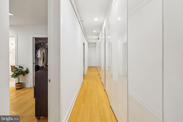 hallway with light wood finished floors, baseboards, and recessed lighting