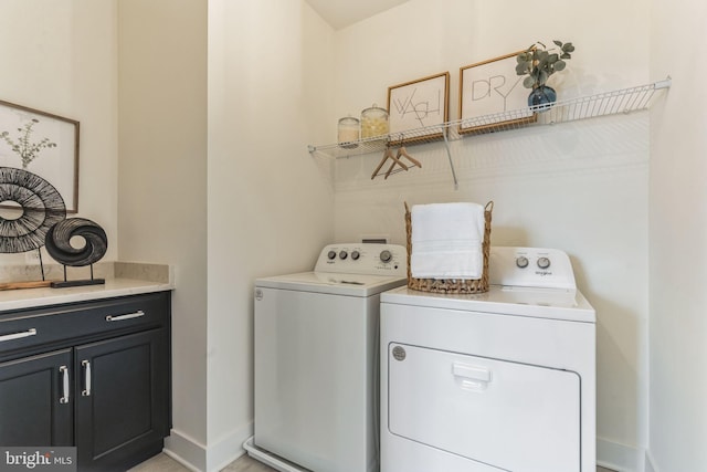 clothes washing area featuring cabinets and separate washer and dryer