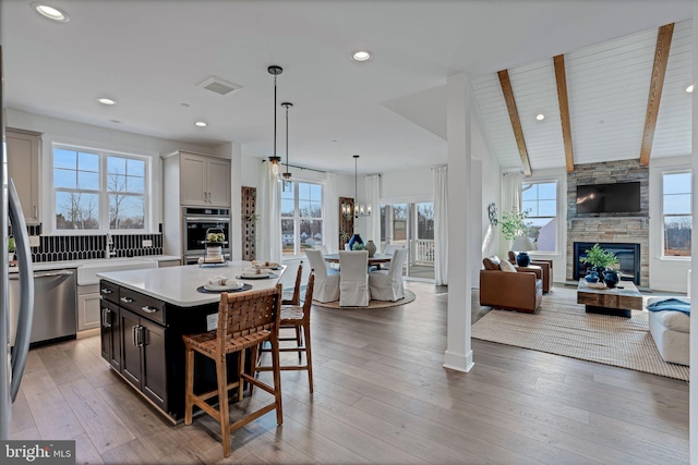 kitchen featuring a fireplace, lofted ceiling with beams, a center island, and a wealth of natural light