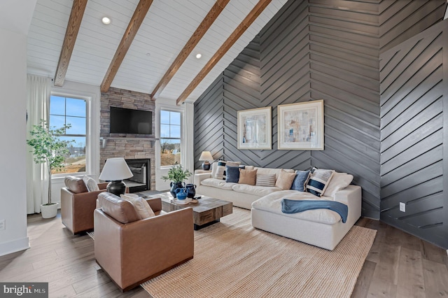 living room with a stone fireplace, light hardwood / wood-style flooring, wood walls, and high vaulted ceiling