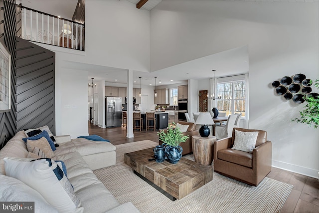 living room featuring a towering ceiling, a chandelier, and hardwood / wood-style floors