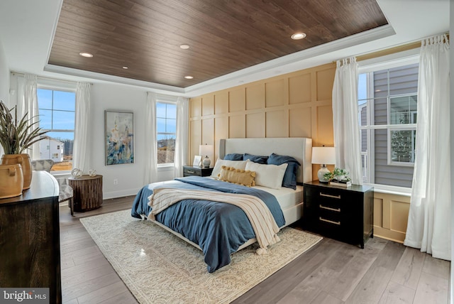 bedroom with wooden ceiling, a raised ceiling, crown molding, and hardwood / wood-style flooring