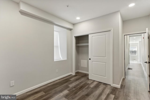 unfurnished bedroom with a closet and dark hardwood / wood-style flooring