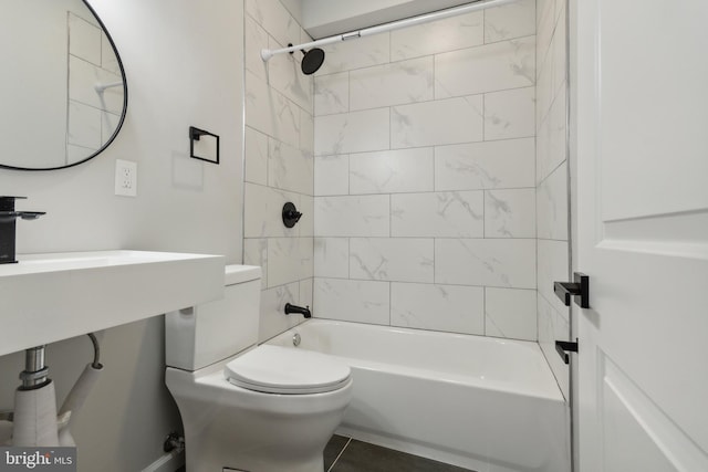 bathroom with tile patterned flooring, tiled shower / bath combo, and toilet