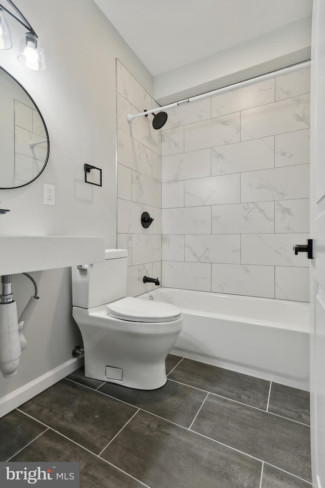 bathroom with tiled shower / bath combo, tile patterned floors, and toilet